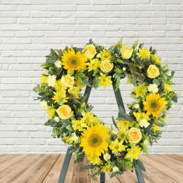 Heart-shaped floral wreath with yellow sunflowers and roses on a stand