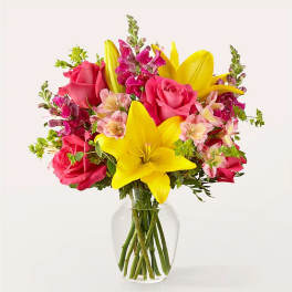 Pink roses and yellow lilies in a clear glass vase