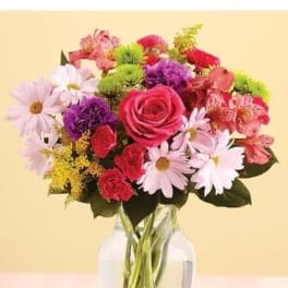 Mixed bouquet of pink roses, daisies, and carnations in a glass vase