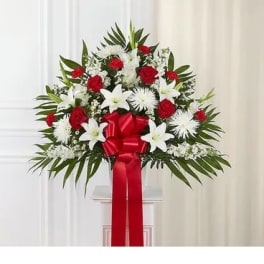 Standing floral spray with red roses, white lilies, and a red ribbon