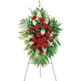 Standing floral spray with red carnations and white flowers on an easel
