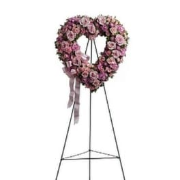 Heart-shaped pink rose funeral wreath on a metal stand