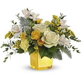 Yellow and white rose arrangement in a square glass vase