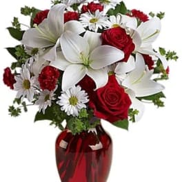 Red roses and white lilies in a red glass vase