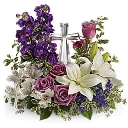 Purple and white floral arrangement with roses and lilies around a silver ribbon centerpiece