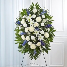 Standing funeral spray of white and blue flowers on an easel