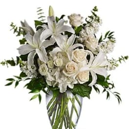White lilies and roses arranged in a clear glass vase