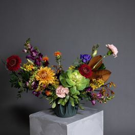 Colorful mixed flower arrangement in a dark vase on a pedestal