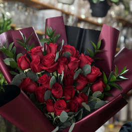 Bouquet of red roses wrapped in burgundy paper with a red ribbon