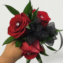 Handheld bouquet of red roses with black ribbon and green leaves