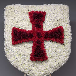 Heart-shaped floral tribute with a red cross on a white flower background