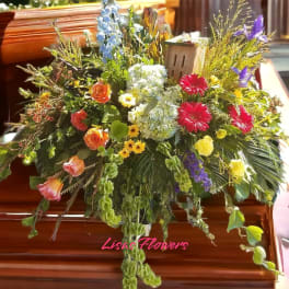 Large colorful floral spray on a casket with roses and daisies