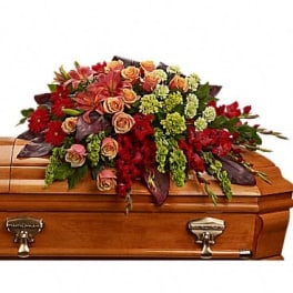 Red and peach floral spray arranged on a wooden casket