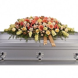Large floral casket spray with peach, cream, and pink blooms