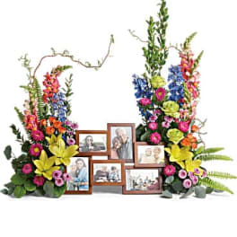 Colorful floral memorial display with framed photos in the center