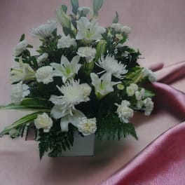 White lilies and chrysanthemums arranged in a white container