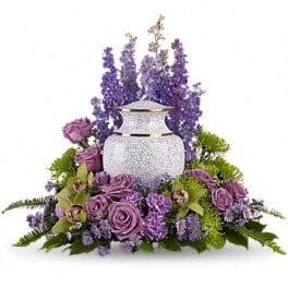 Purple floral arrangement around a white urn-shaped vase