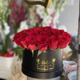 Red roses arranged in a black round box with gold lettering