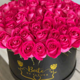 Hot pink roses arranged in a black round box
