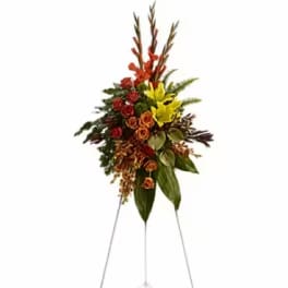 Tall standing floral spray with red, yellow, and orange flowers on a metal easel