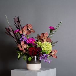Mixed bouquet in a two-tone ceramic vase with pink, purple, and red flowers
