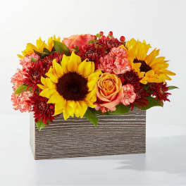 Sunflowers, roses, and carnations in a rectangular wooden box