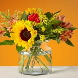 Sunflower and mixed flower bouquet in a clear glass vase
