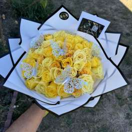 Bouquet of yellow roses wrapped in white paper with butterfly decorations