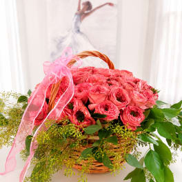 Pink roses in a wicker basket with a pink ribbon