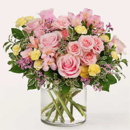 Pink roses and yellow carnations in a clear glass vase