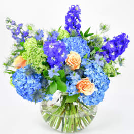 Blue and peach flower arrangement in a clear glass vase