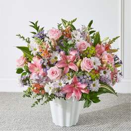 Pink roses and lilies arranged with daisies in a white vase