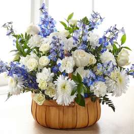 White and blue floral arrangement in a wooden basket