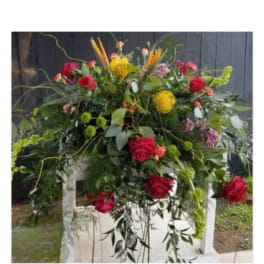 Large mixed floral arrangement with red roses and yellow blooms