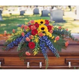 Colorful casket spray with sunflowers, red gerberas, and blue flowers