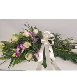 White roses and purple orchids arranged with a white ribbon