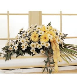 Yellow and white daisy arrangement with a yellow ribbon on a bed frame