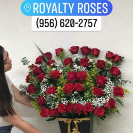 Large red rose arrangement in a black vase with a gold ribbon