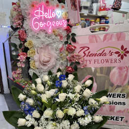 Large white rose arrangement in a white container with blue ribbon