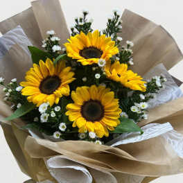 Bouquet of sunflowers with small white filler flowers wrapped in brown paper