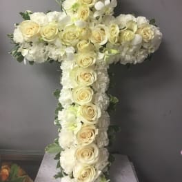 White floral cross with cream roses and white blooms