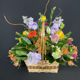 Mixed flower basket with a bird decoration and tall curly branches