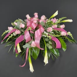 Pink rose bouquet with white calla lilies and ribbon on a dark background