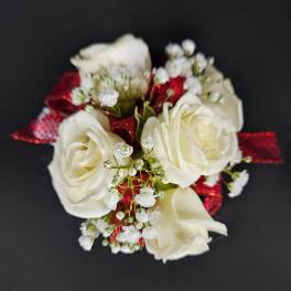 Small cluster of white roses with baby's breath and red ribbon on a dark background