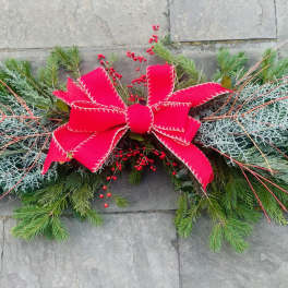 Long evergreen swag with red berries and a large red bow in the center