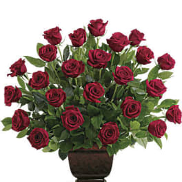 Red roses arranged in a dark pedestal vase
