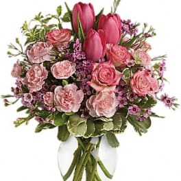 Pink tulips and roses arranged in a clear glass vase