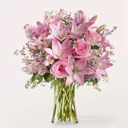 Pink lilies and roses arranged in a clear glass vase