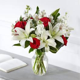 Red roses and white lilies arranged in a clear glass vase