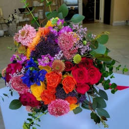 Colorful hand-tied bouquet of roses and mixed blooms in bright pink, orange, yellow, and purple tones